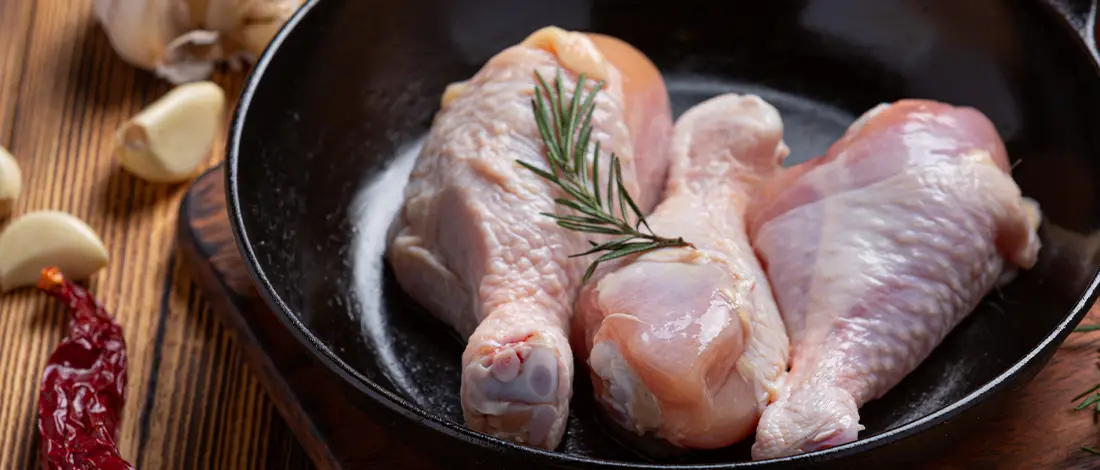Raw chicken drumsticks on a pan