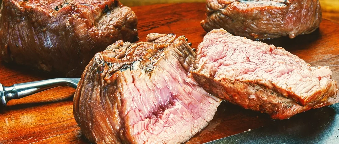 Cooked sliced up steak on a wooden board