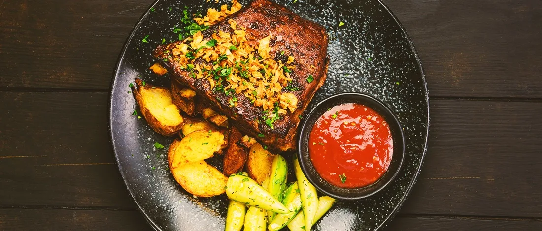 Cooked ribs with condiments and side dishes on the side