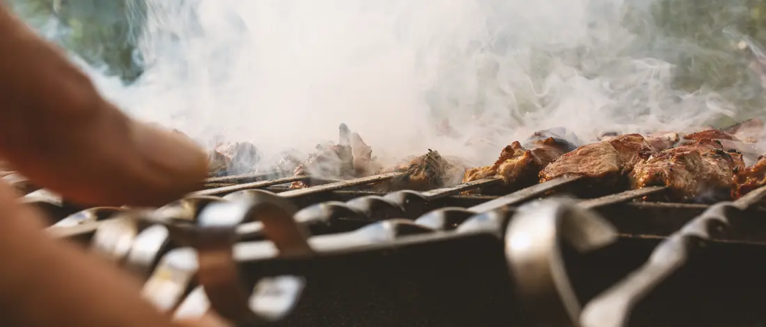 A person cooking meat on a grill