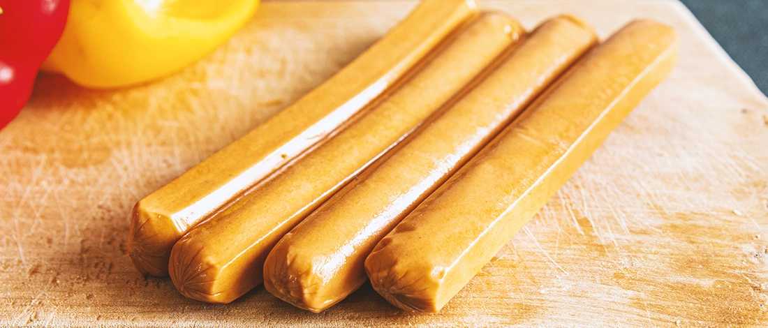 Four chicken sausages on a wooden chopping board