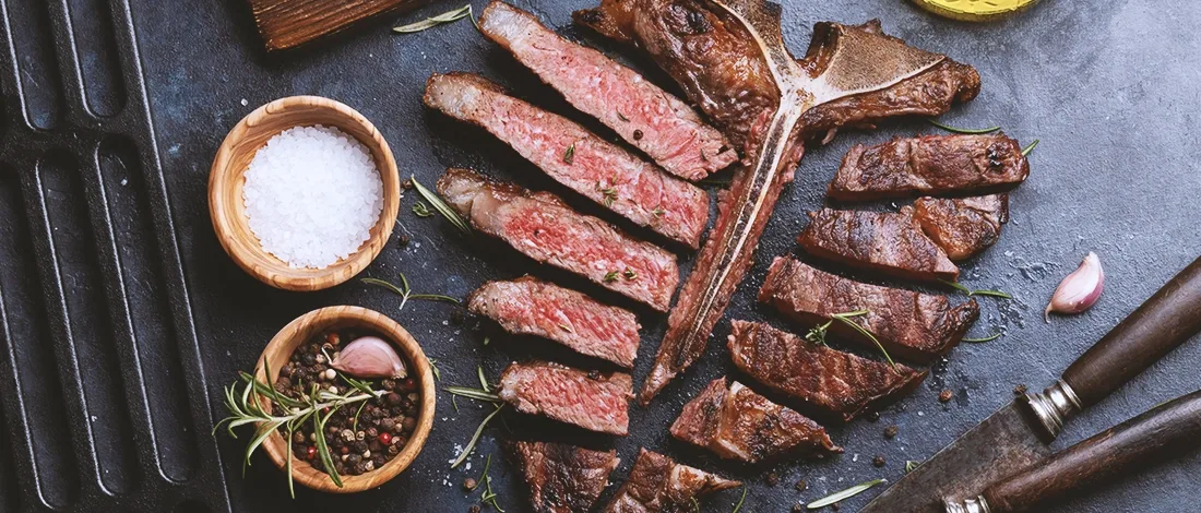 Top view of sliced up meat with herbs and salt on the side