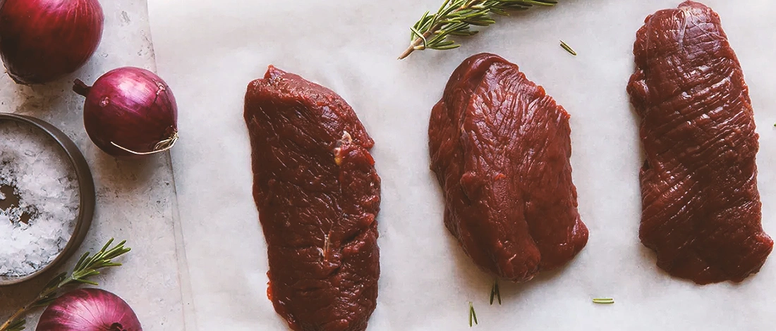A row of venison meat and onions on the side