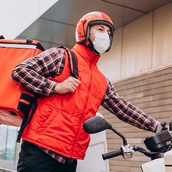 A delivery guy on a motorcycle wearing orange outfit