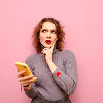 A woman thinking while holding a phone