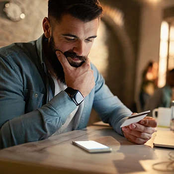 A guy thinking while holding a credit card and looking at his phone
