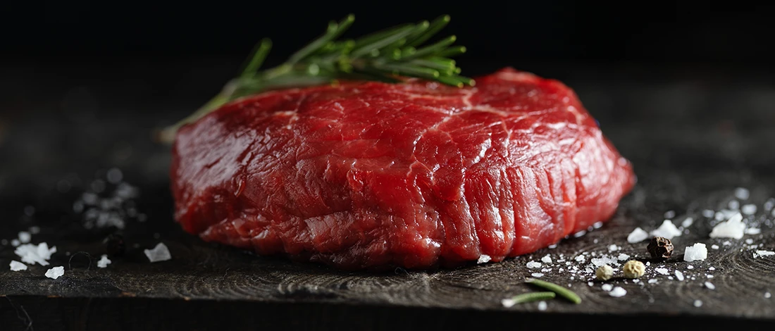 A close up image of raw red meat on a black slate