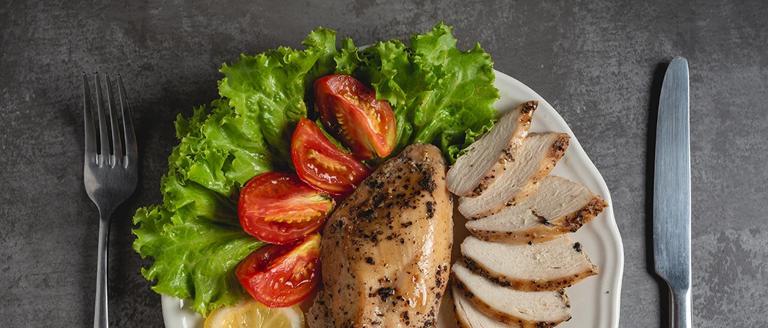 A top view image of grilled chicken with vegetables on a plate