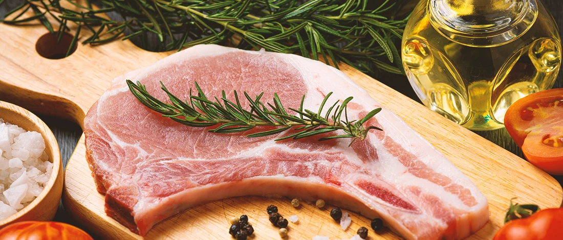 An image of raw pork chop on a wooden board
