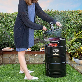 An image of a woman using a drum smoker outdoors